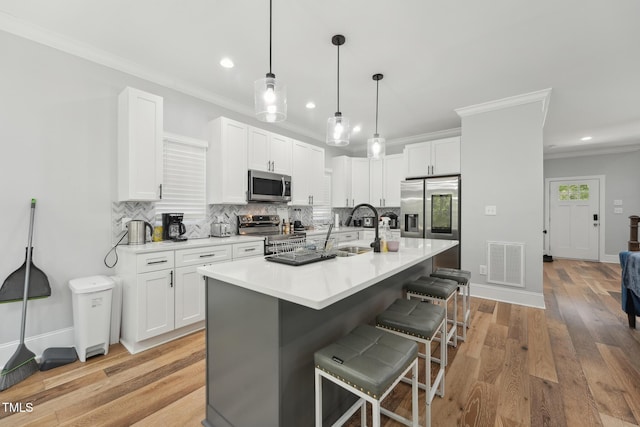 kitchen with a kitchen breakfast bar, backsplash, visible vents, a sink, and appliances with stainless steel finishes