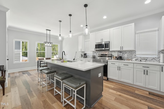 kitchen featuring stainless steel appliances, a sink, a kitchen island with sink, tasteful backsplash, and a breakfast bar area