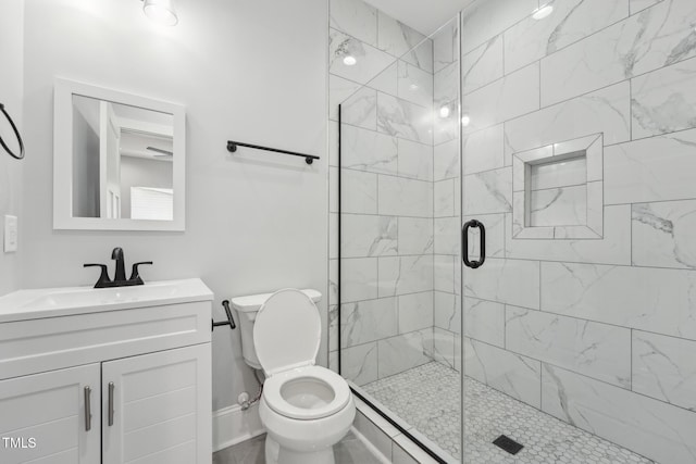 bathroom featuring baseboards, a shower stall, toilet, and vanity