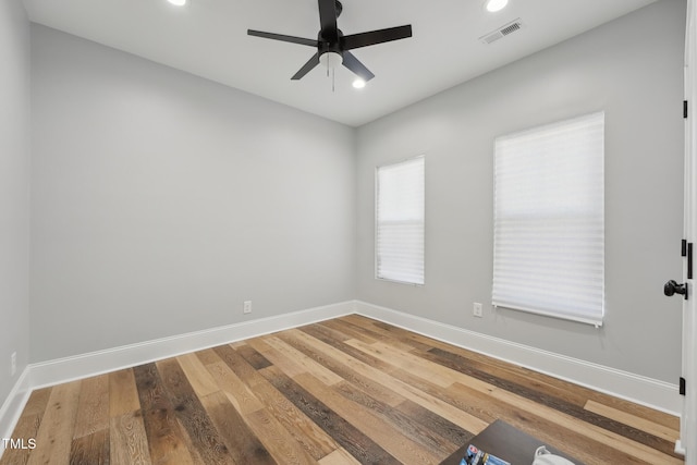 empty room with wood finished floors, visible vents, baseboards, and ceiling fan