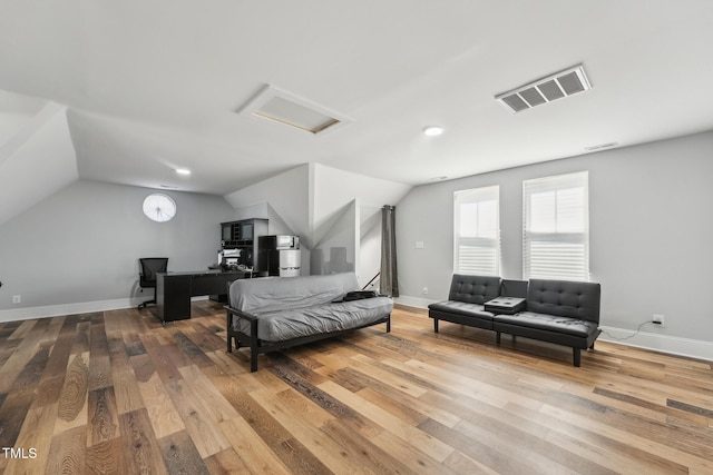 bedroom featuring attic access, vaulted ceiling, wood finished floors, and visible vents