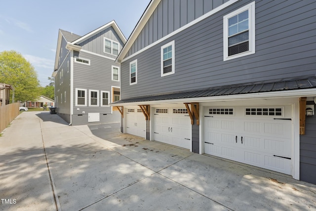 back of property with board and batten siding, an attached garage, and driveway