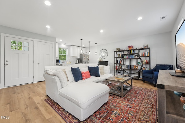living room with light wood-type flooring, visible vents, and recessed lighting