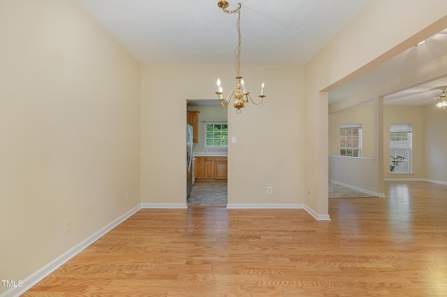 1031 Lake Moraine Pl, Raleigh, NC 27607 - spare room featuring a chandelier, light wood finished floors, a ceiling fan, and baseboards