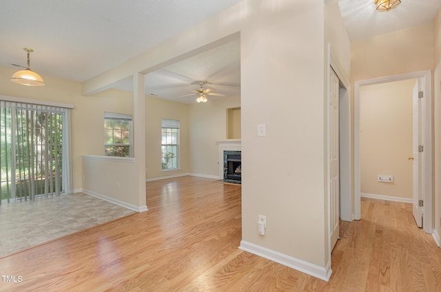 1031 Lake Moraine Pl, Raleigh, NC 27607 - unfurnished living room featuring ceiling fan, light wood-style flooring, baseboards, and a fireplace
