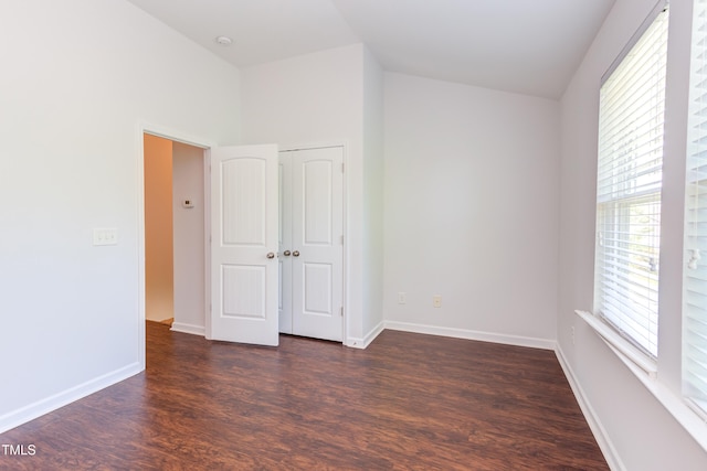 empty room with baseboards, a healthy amount of sunlight, and dark wood-type flooring