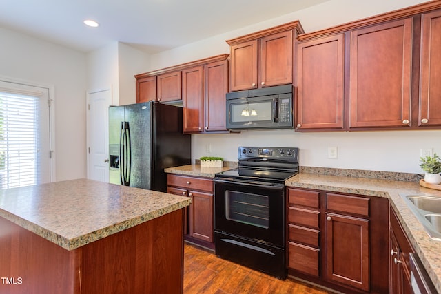 kitchen with a kitchen island, recessed lighting, light countertops, dark wood finished floors, and black appliances