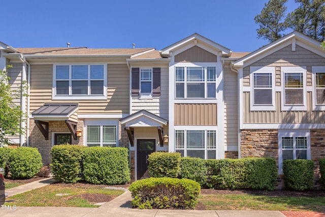 townhome / multi-family property featuring board and batten siding, roof with shingles, and stone siding