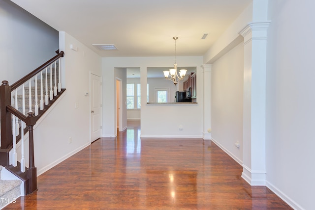 unfurnished living room featuring baseboards, dark wood-style flooring, a chandelier, and stairway