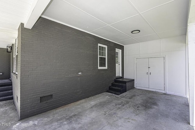 exterior space featuring unfinished concrete flooring and brick wall