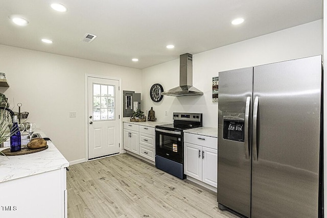 kitchen featuring white cabinets, visible vents, stainless steel appliances, light wood finished floors, and wall chimney exhaust hood
