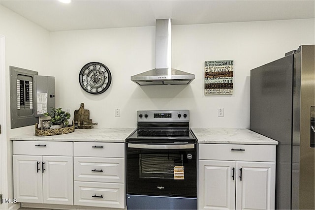 kitchen with light stone counters, wall chimney range hood, white cabinets, appliances with stainless steel finishes, and electric panel