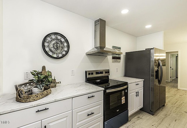 kitchen with wall chimney exhaust hood, light wood finished floors, stainless steel appliances, and light stone countertops