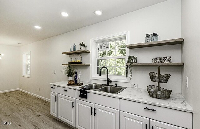 bar with recessed lighting, light wood-style flooring, baseboards, and a sink