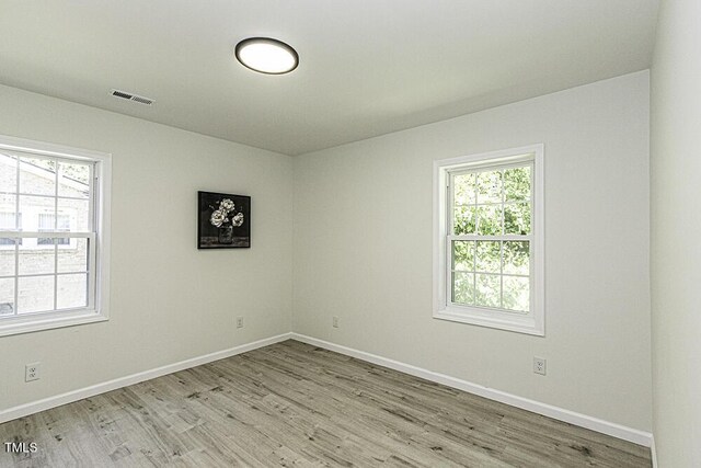 spare room with baseboards, visible vents, and light wood finished floors