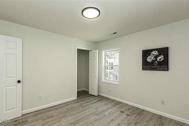 unfurnished bedroom with baseboards, light wood-type flooring, and visible vents