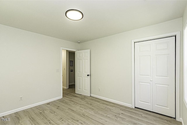 unfurnished bedroom featuring a closet, baseboards, and light wood-type flooring