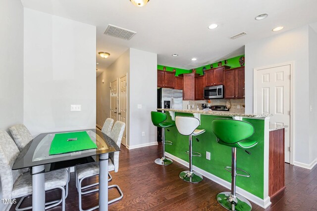 412 Stone Flower Ln, Raleigh, NC 27603 - kitchen featuring stainless steel appliances, dark wood-style floors, a breakfast bar area, a center island, and decorative backsplash