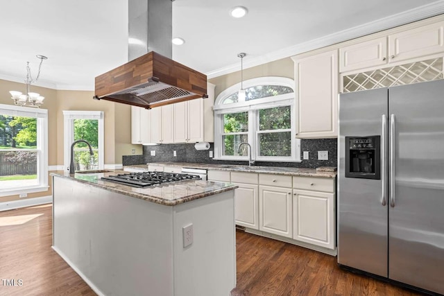 kitchen featuring a kitchen island with sink, crown molding, gas cooktop, stainless steel refrigerator with ice dispenser, and island range hood