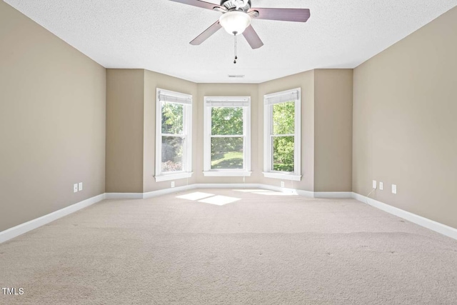 spare room featuring carpet flooring, ceiling fan, visible vents, baseboards, and a textured ceiling