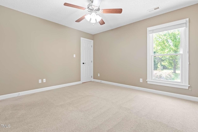 spare room with baseboards, visible vents, light carpet, and ceiling fan