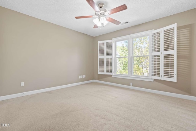 carpeted spare room with baseboards, visible vents, a ceiling fan, and a textured ceiling