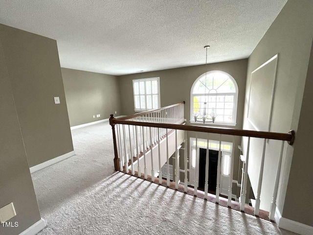 102 Traviliah Oaks Ln, Cary, NC 27518 - hallway featuring carpet, an upstairs landing, baseboards, a textured ceiling, and a chandelier