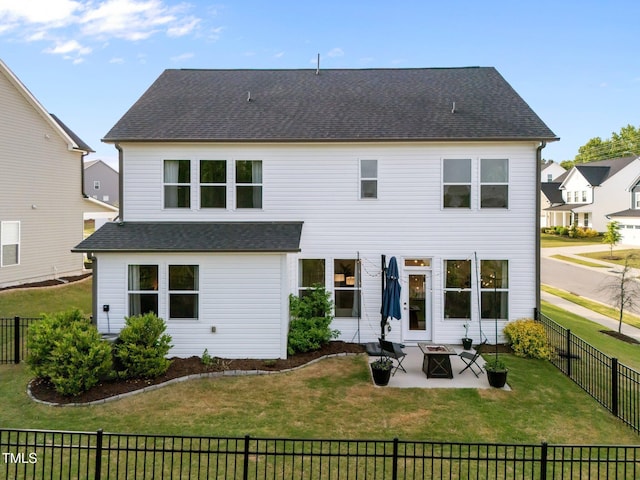 rear view of property with a lawn, a patio area, a fenced backyard, an outdoor fire pit, and a shingled roof