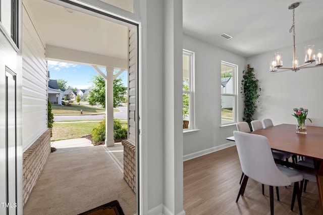 dining space featuring baseboards, visible vents, wood finished floors, and a chandelier