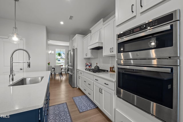 kitchen with visible vents, appliances with stainless steel finishes, wood finished floors, a sink, and white cabinetry