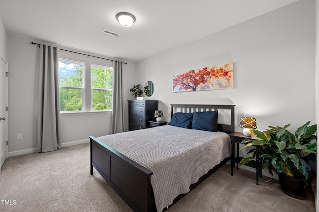 bedroom featuring baseboards, visible vents, and light colored carpet