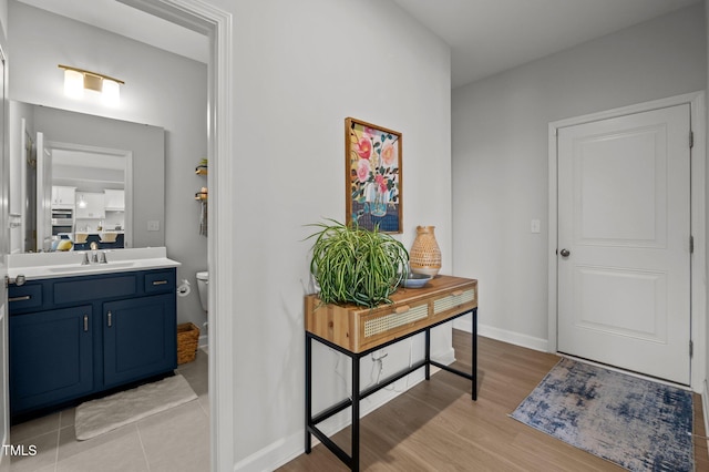 doorway featuring baseboards, a sink, and light wood-style flooring