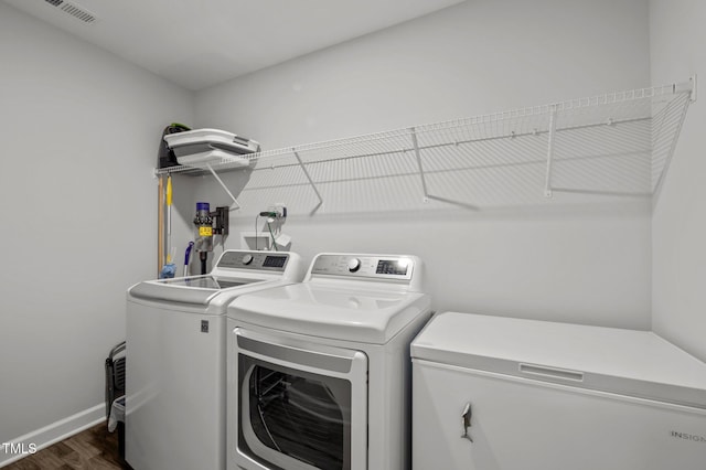 clothes washing area with independent washer and dryer, dark wood-style flooring, laundry area, baseboards, and visible vents