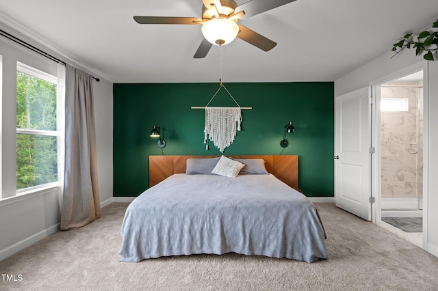 carpeted bedroom with baseboards, a ceiling fan, ensuite bath, and multiple windows