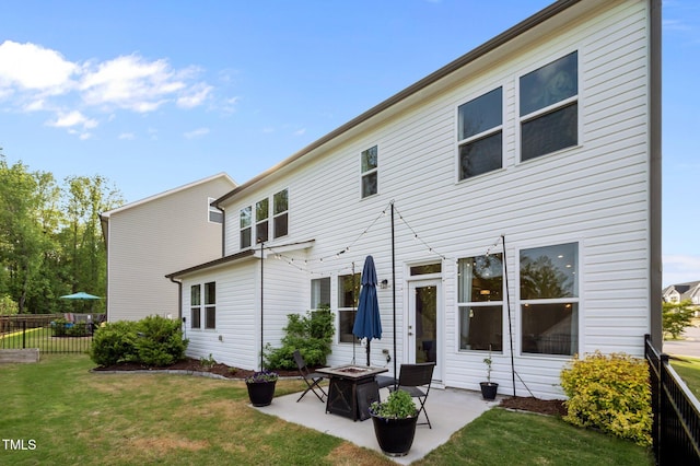 back of house featuring a fire pit, a patio area, fence, and a yard