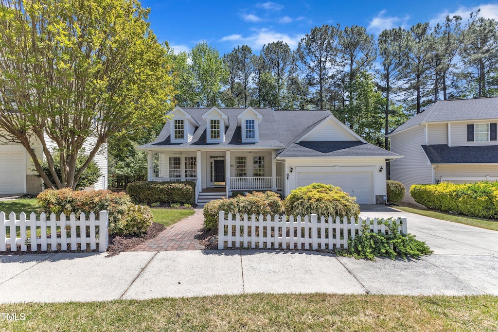 cape cod-style house featuring driveway, a porch, fence private yard, and a garage