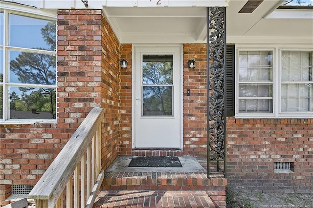 entrance to property with a porch and brick siding