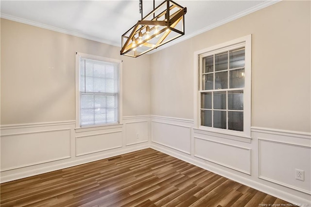 unfurnished dining area with wainscoting, a decorative wall, ornamental molding, and dark wood-type flooring