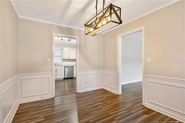 unfurnished dining area with crown molding, dark wood-style floors, a notable chandelier, and wainscoting