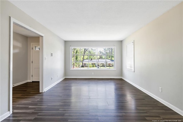 empty room with dark wood-type flooring and baseboards