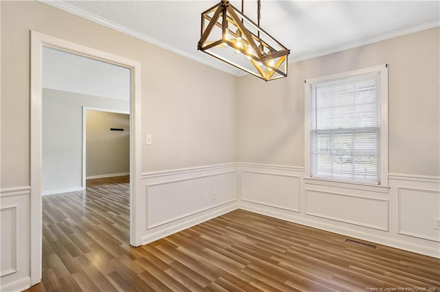 unfurnished dining area featuring wood finished floors, visible vents, a chandelier, and crown molding