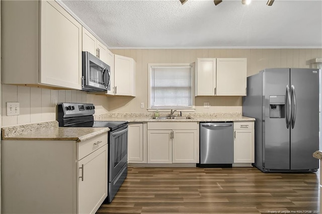 kitchen featuring stainless steel appliances, ornamental molding, a sink, a textured ceiling, and dark wood-style flooring