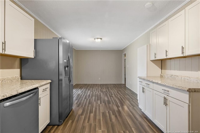 kitchen featuring appliances with stainless steel finishes, white cabinets, ornamental molding, light stone countertops, and dark wood-type flooring