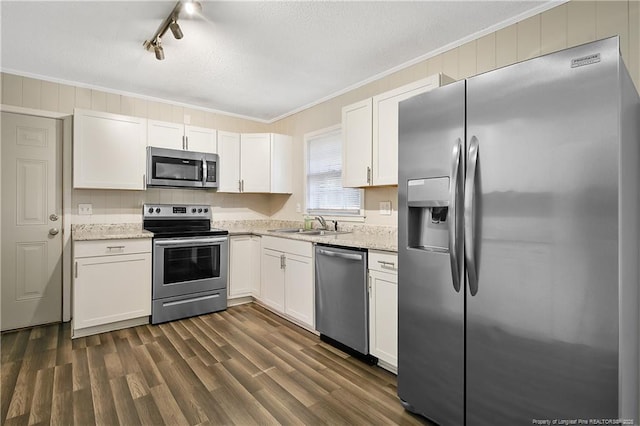 kitchen with stainless steel appliances, rail lighting, ornamental molding, a sink, and white cabinetry