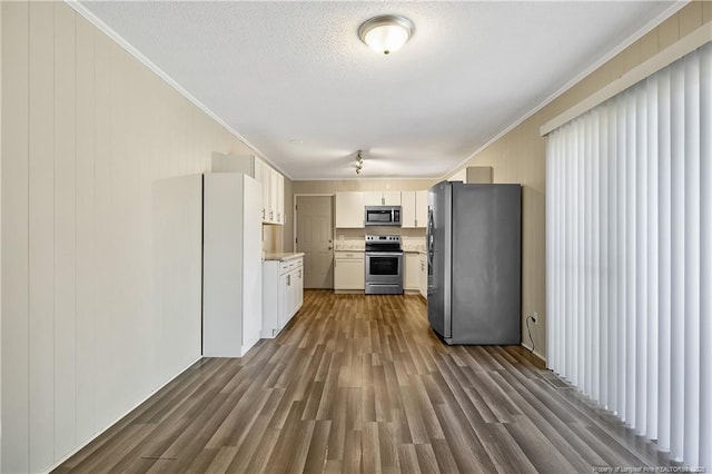 kitchen featuring white cabinets, dark wood-style floors, light countertops, crown molding, and appliances with stainless steel finishes