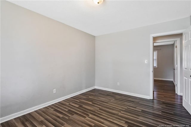 empty room featuring baseboards and dark wood-style floors