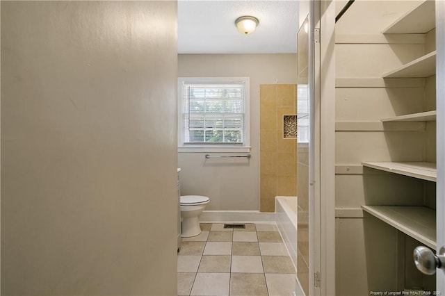 bathroom featuring a tub, baseboards, toilet, tile patterned flooring, and visible vents