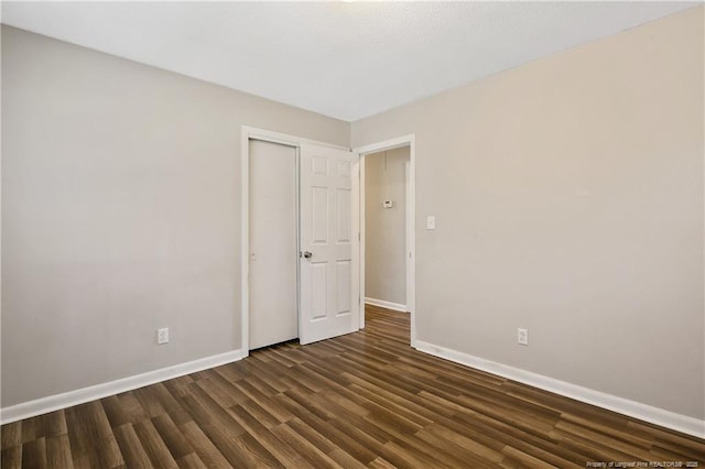unfurnished room featuring baseboards and dark wood finished floors