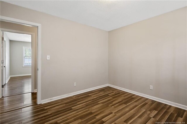 empty room featuring baseboards and dark wood-style flooring