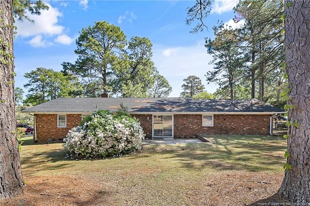 back of property with a patio area, brick siding, and a yard